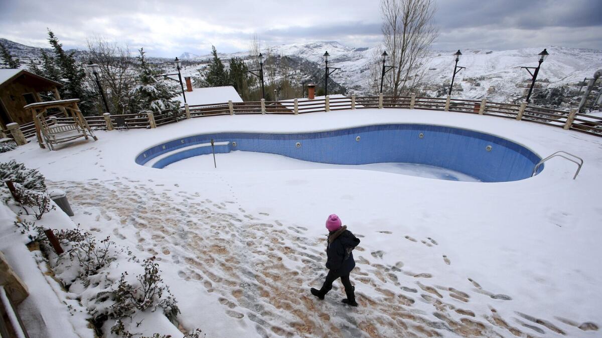 A girl walks past a snow-covered swimming pool in the town of Jezzine, southern Lebanon, January 25, 2016. Reuters