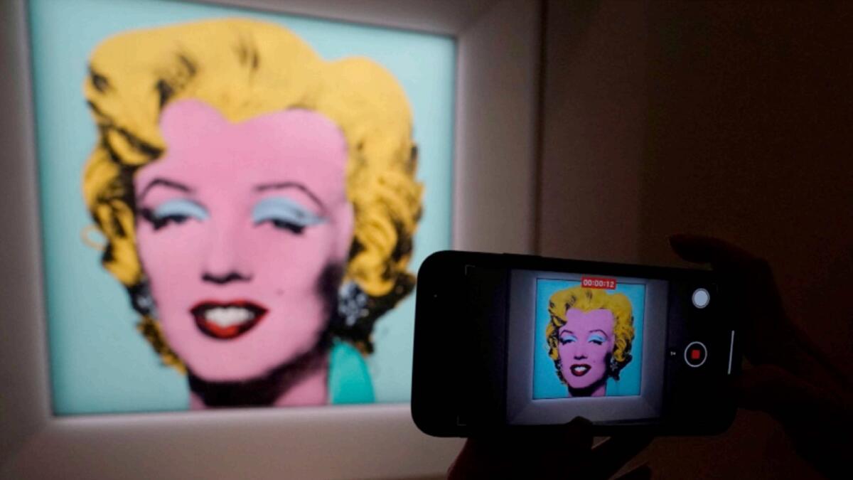 A journalist takes photos of Andy Warhol's 1964 Shot Sage Blue Marilyn during a press preview in New York. — AFP