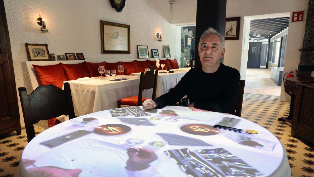 Spanish chef Ferran Adria poses sitting at a table with video projections in the former dining room of the El Bulli restaurant transformed into 'elBulli1846' Museum during an interview with AFP, in Roses, near Barcelona on May 24, 2023. — AFP
