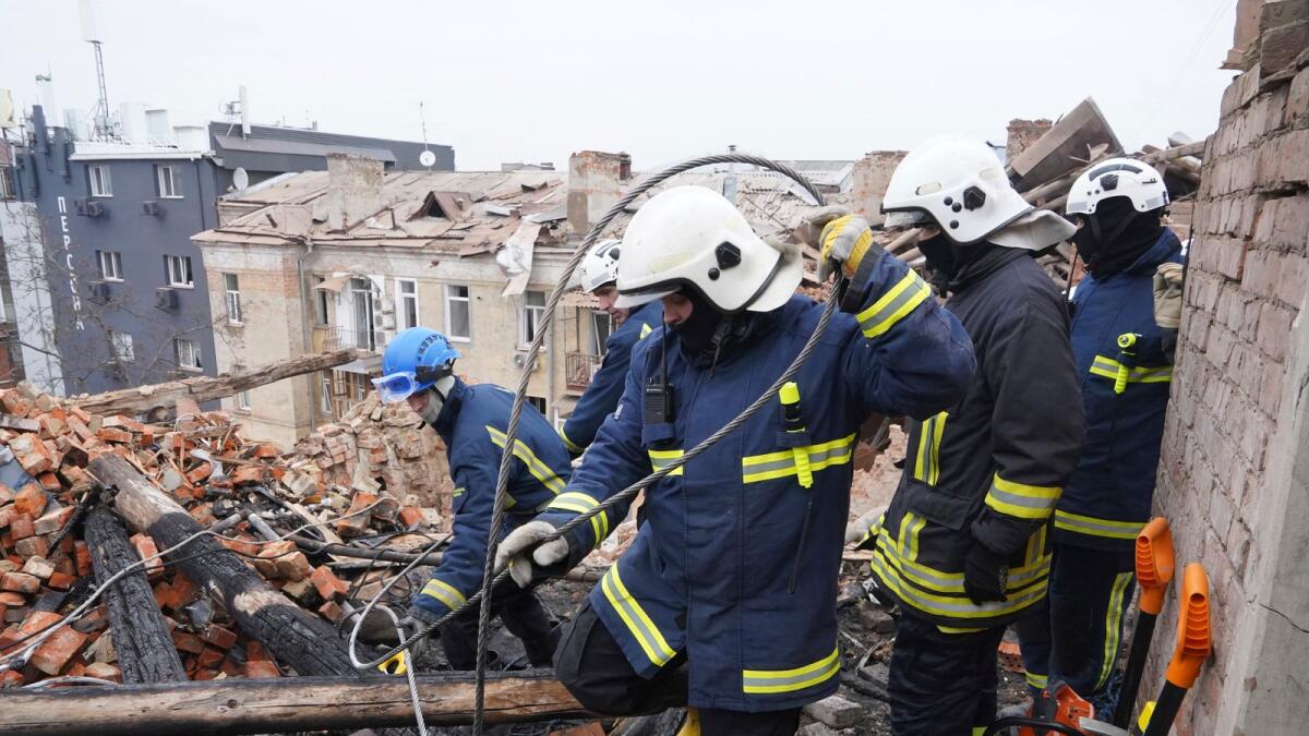 Ukrainian emergency workers clear the rubble on the roof of a residential building which was hit by a Russian rocket at the city center of Kharkiv, Ukraine, on Monday. — AP