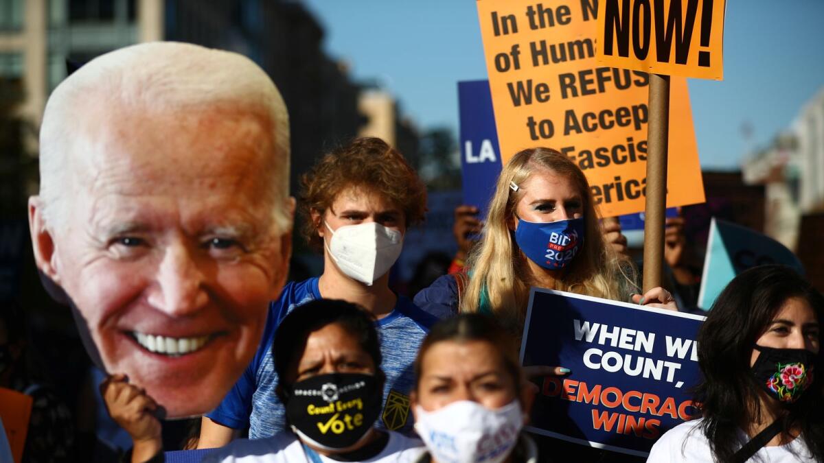 A supporter of Democratic U.S. presidential nominee Joe Biden holds a cardboard cutout of him as others gather at Black Lives Matter Plaza, near the White House after Election Day in Washington, D.C., U.S., November 6, 2020.