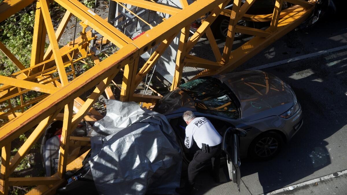A member of the Seattle police department inspects one of the cars crushed by part of a construction crane on Mercer Street, which killed four people and injured several others in Seattle, Washington, US.- Reuters
