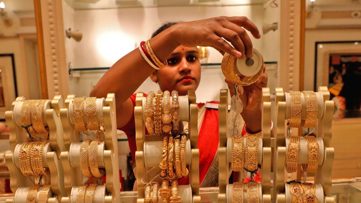 A saleswoman shows gold bangles to a customer at a jewellery showroom in Kolkata, India. - Reuters file