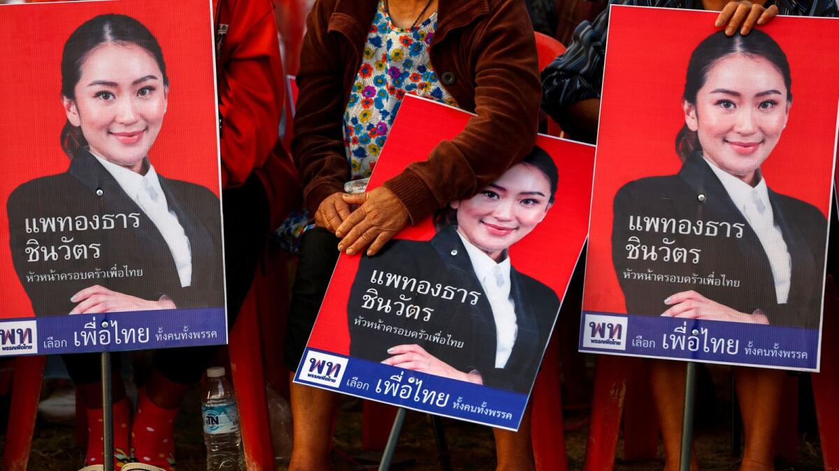 Supporters hold posters of Paetongtarn Shinawatra, 36, the Pheu Thai Party's most visible candidate for prime minister, during the general election campaign in Ubon Ratchathani province, Thailand. — Reuters