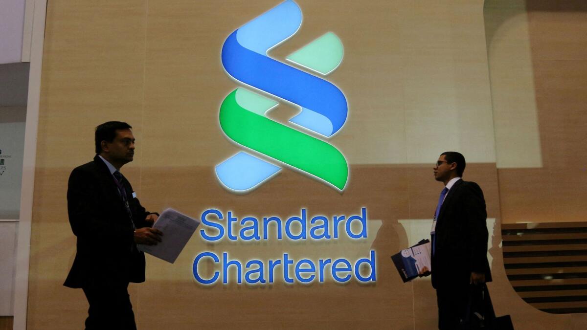 People pass by a logo of Standard Chartered in Toronto. - Reuters