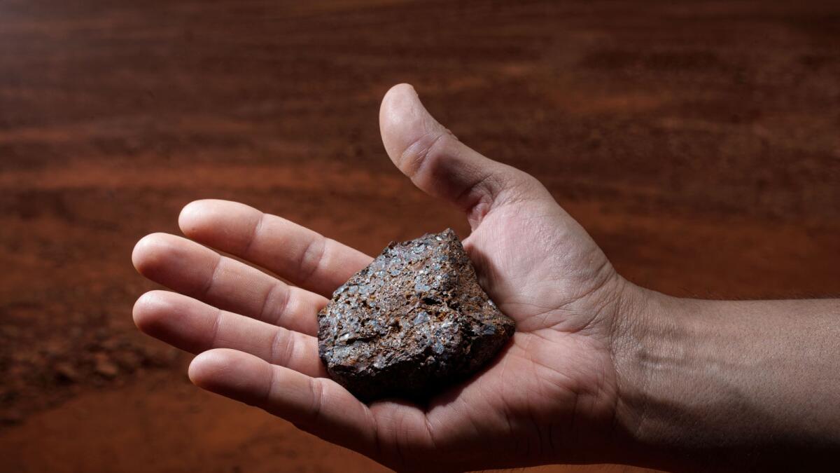A piece of iron ore on the site of the Christmas Creek mine in Western Australia, a region that is the world’s largest iron ore exporter. A plan to cover an expanse of land in remote Western Australia that is eight times as large as New York City with some 10 million solar panels, and as many as 1,743 huge wind turbines, would manufacture green hydrogen fuel to replace the dirty fossil fuels used by ore mining operations. (Giacomo d'Orlando/The New York Times)