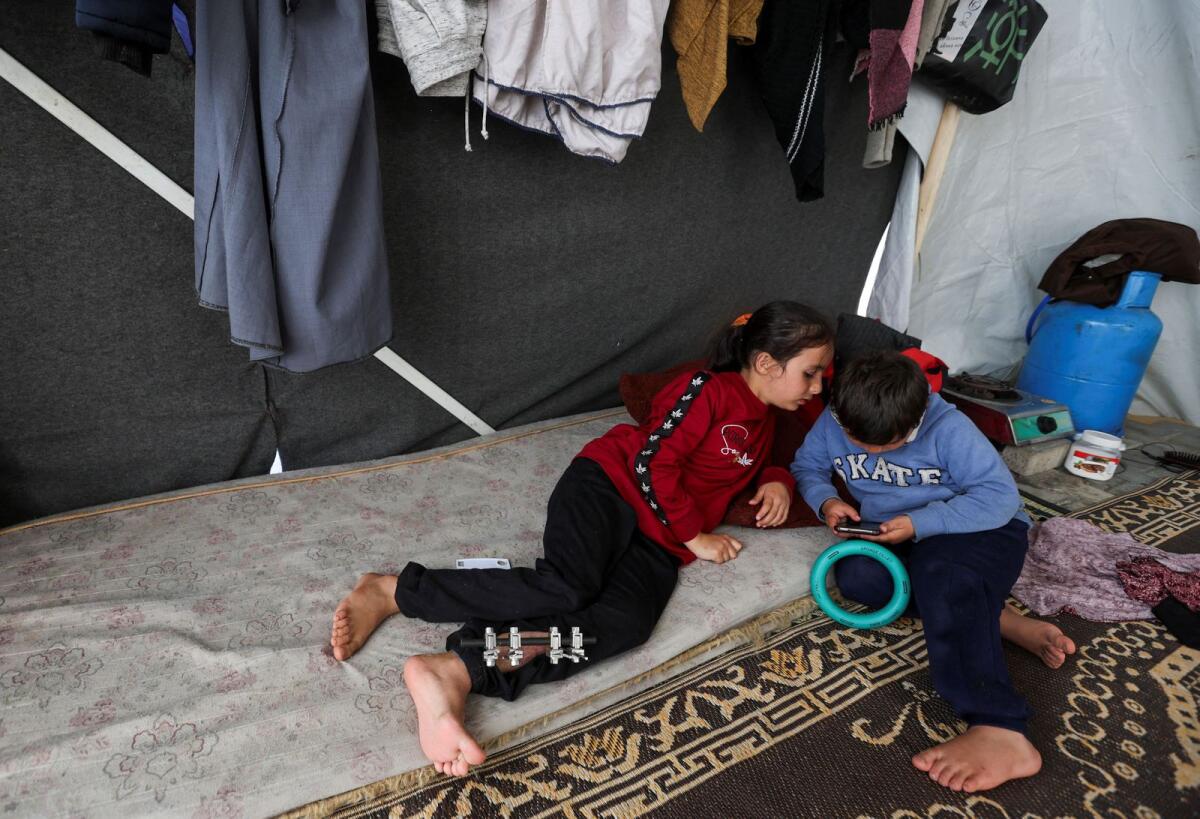 Laila Al Sultan, a displaced Palestinian girl who was wounded in an Israeli strike that killed her father, plays with her brother Khaled inside their makeshift shelter in Rafah in the southern Gaza Strip, on January 8, 2024. — Reuters