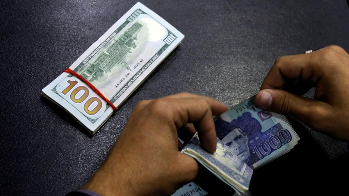 A currency trader counts Pakistani Rupee notes as he prepares an exchange of U.S dollars in Islamabad. - Reuters file