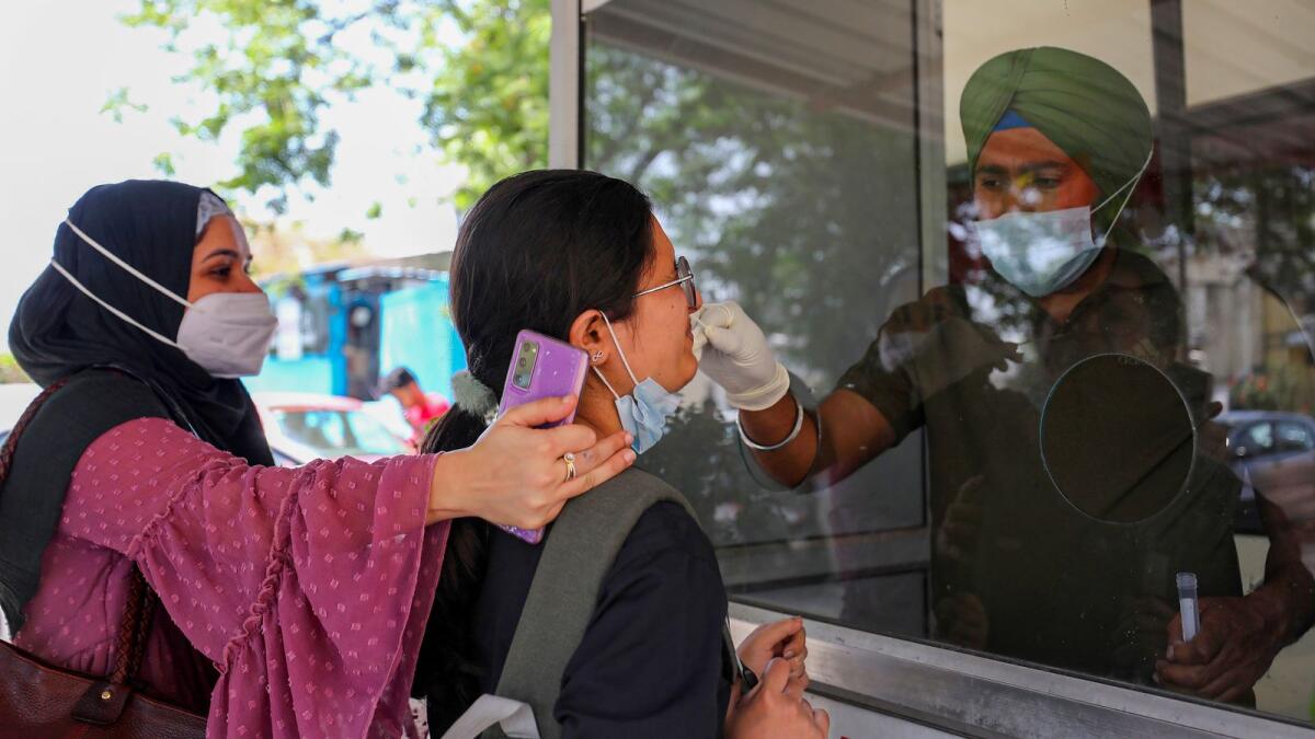 A healthcare worker collects a swab sample of a woman for Covid-19 test, amid a rise in coronavirus cases in the country in Jammu on Wednesday. — PTI