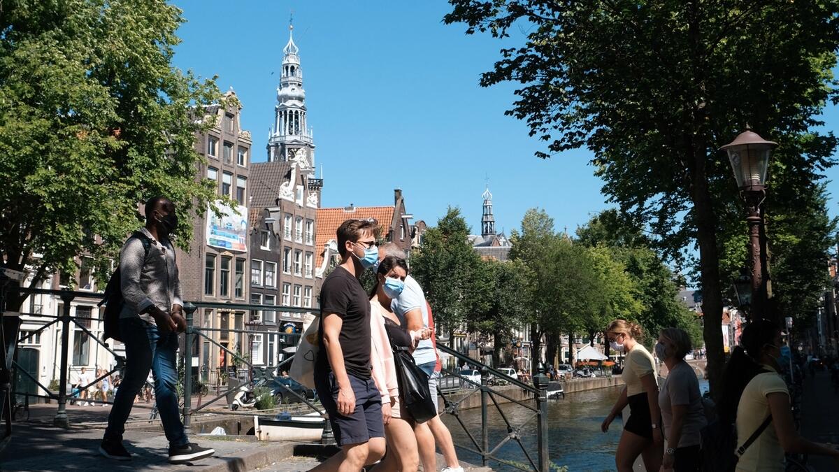 People wearing facemasks to prevent the spread of the coronavirus walk through Amsterdam. The Netherlands' two most populous cities began ordering people to wear face masks in busy streets on Wednesday amid rising coronavirus infection rates. Photo: AP
