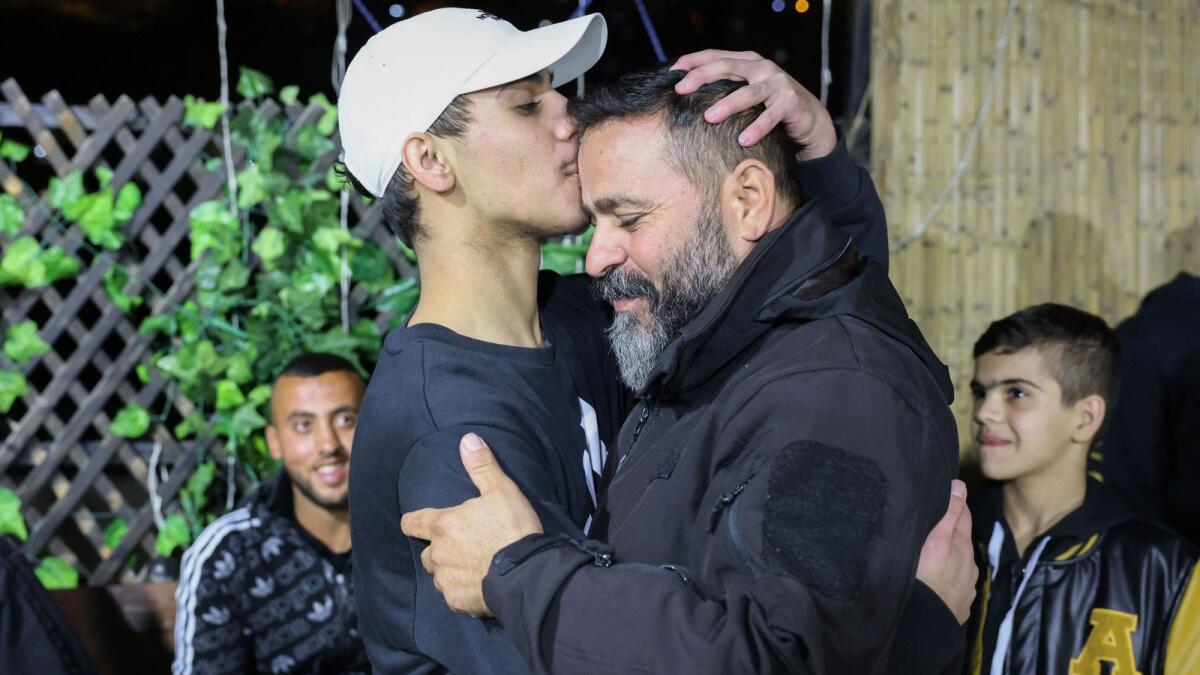 Palestinian Mohammed Al-Awar (L), former prisoner released from an Israeli jail in exchange for hostages freed by Hamas in Gaza, kisses his father's forehead upon return to his home in east Jerusalem, on November 26, 2023. AFP