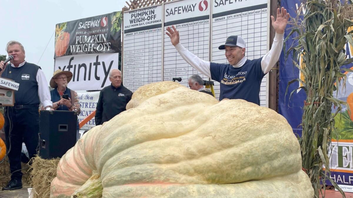 Travis Gienger stands behind his winning pumpkin at the 49th World Championship Pumpkin Weigh-Off in Half Moon Bay. — AP