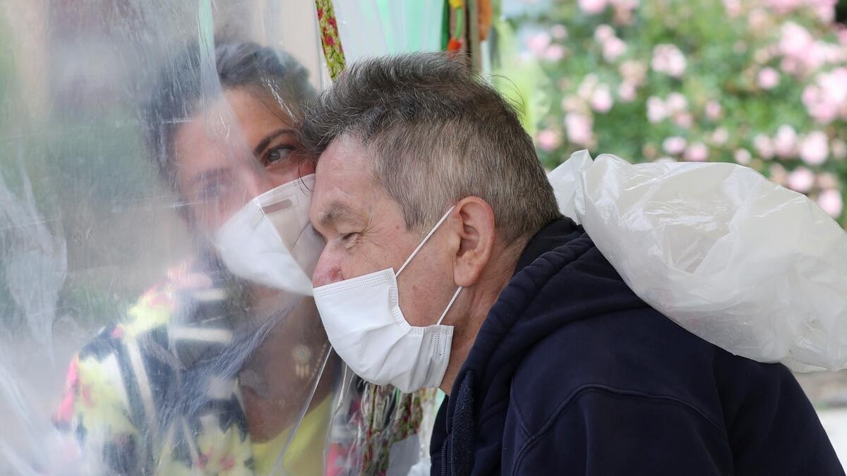 Richard Josefiak, a resident at a Belgian nursing home, hugs his daughter Amandine Josefiak through a wall made with plastic sheets.