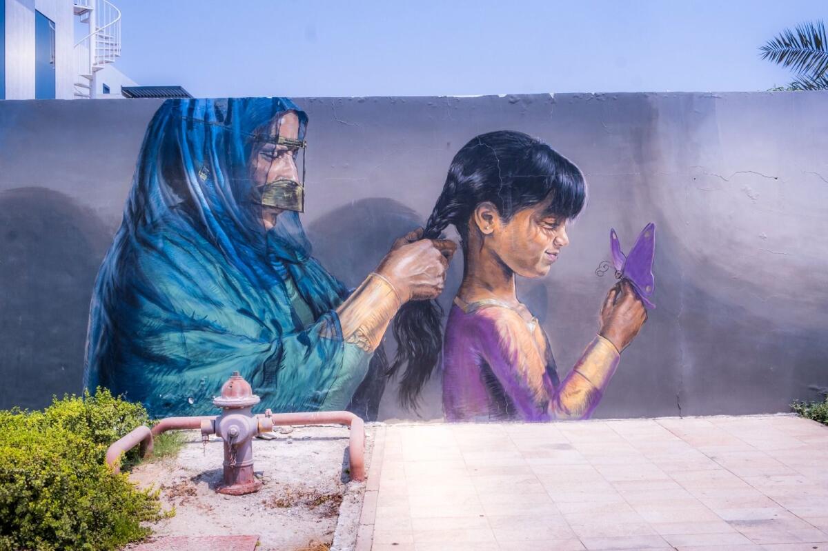 A mural in Dubai shows a mother weaving timeless traditions through her daughter’s hair. Photo: Shihab
