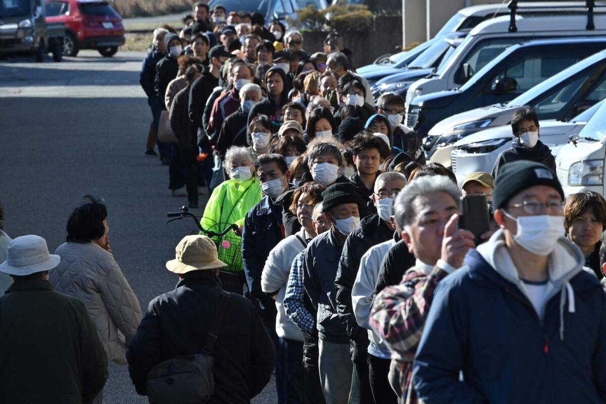 People queue around the Shika Town hall as they wait to receive water at a distribution point in Shika, Ishikawa prefecture on January 2, 2024, a day after a major 7.5 magnitude earthquake struck the Noto region in Ishikawa prefecture. — AFP