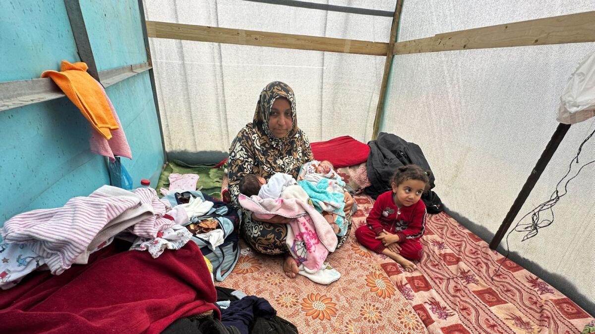 The grandmother of Salma and Alma Al Jadba holds them in a tent. - Reuters