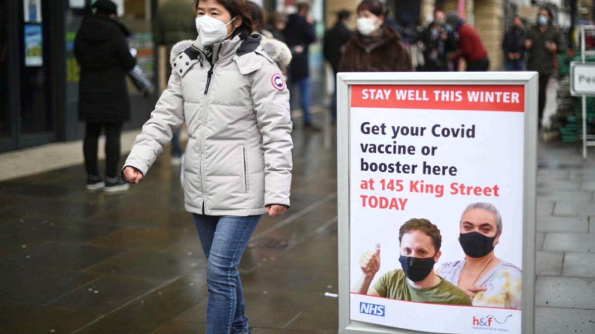 A woman walks past signage outside a pop-up vaccination centre for the Covid-19 vaccine or booster, in Hammersmith and Fulham in Greater London. — AFP