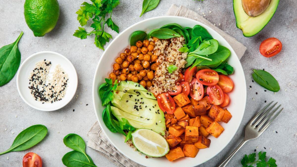 healhty vegan lunch bowl with ingredients. Avocado, quinoa, sweet potato, tomato, spinach and chickpeas vegetables salad. Top view