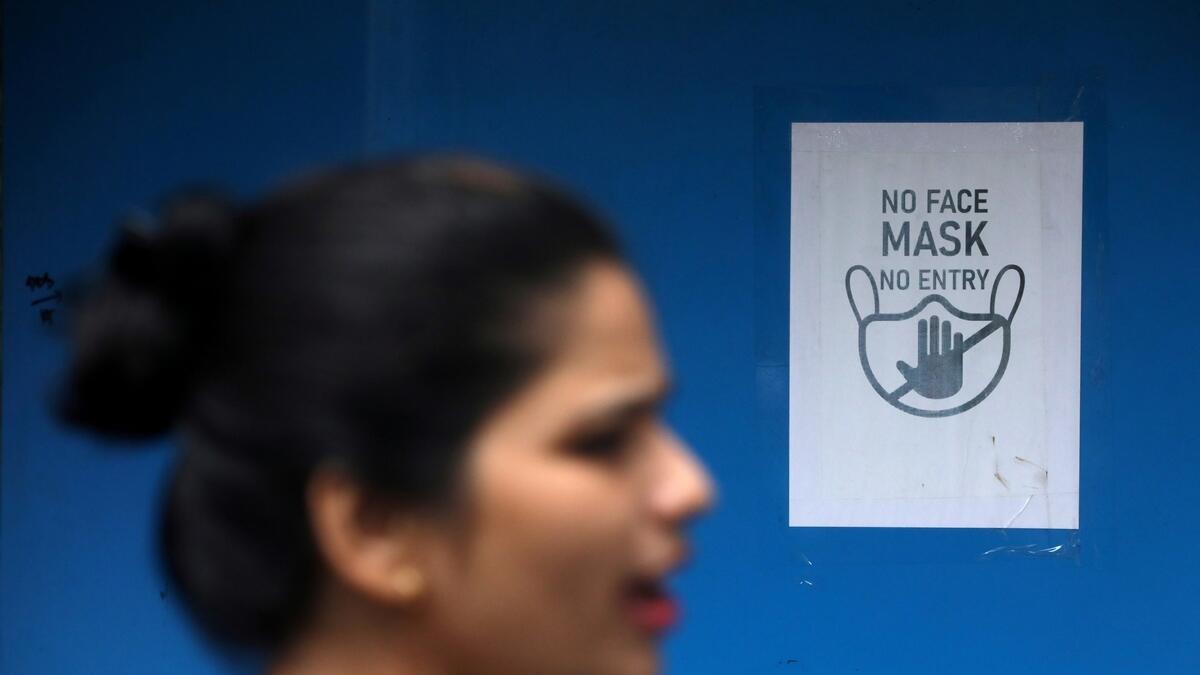A woman walks past a sign put up outside a shop at a market, amidst the spread of the coronavirus disease in Mumbai.