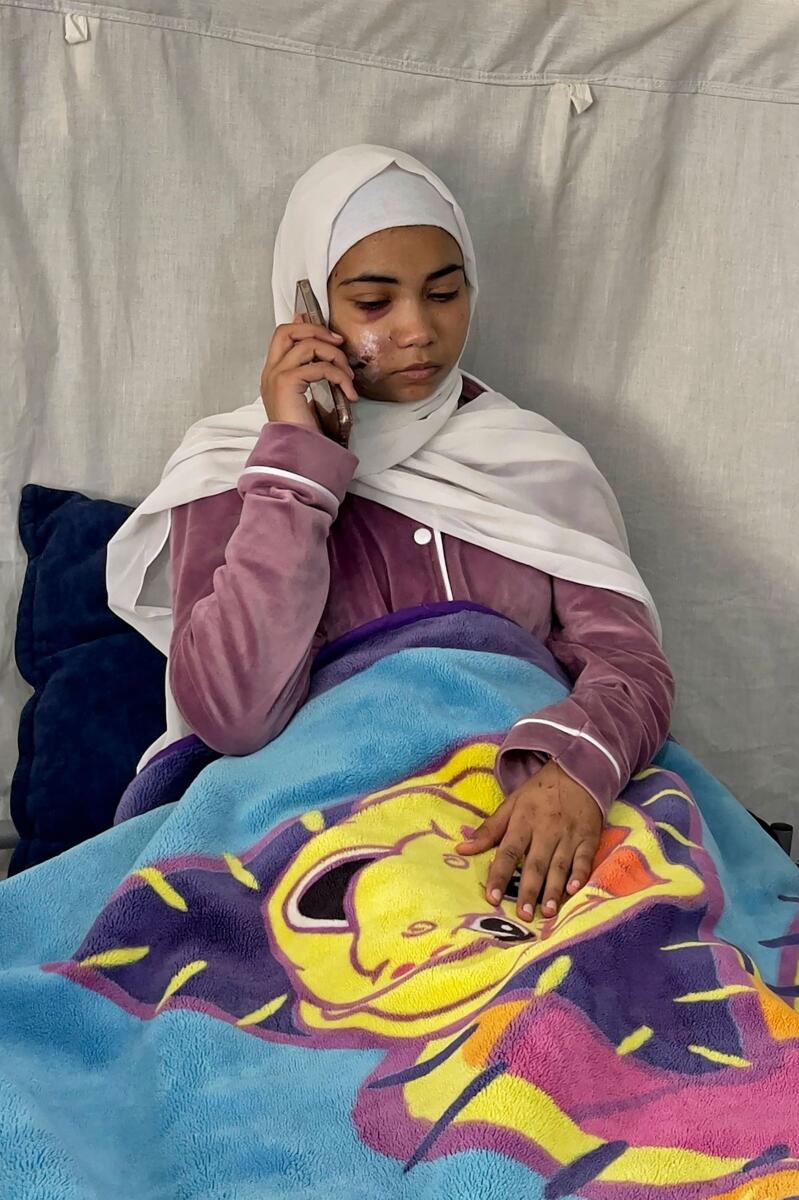 Palestinian girl Hala Hazem Hamada speaking on her mobile phone while taking rest inside a hospital in Rafah. — AFP
