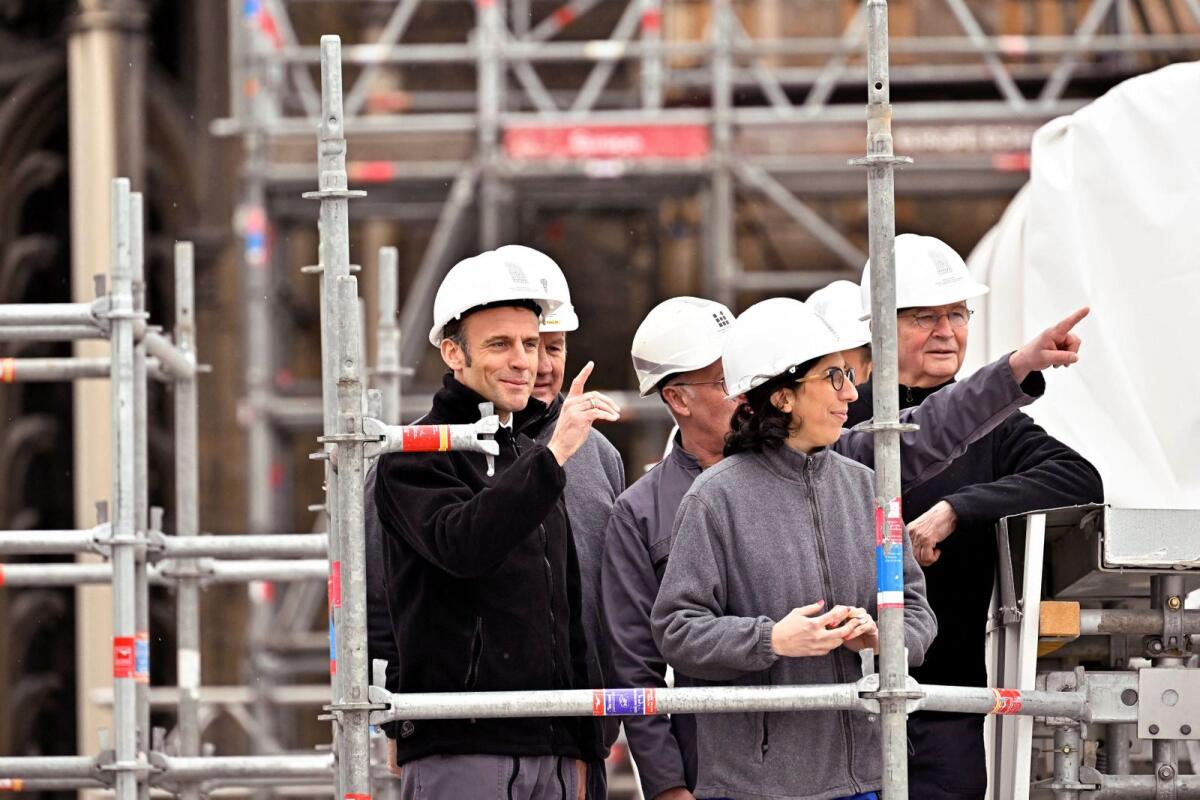 French President Emmanuel Macron and French Culture Minister Rima Abdul Malak, wearing working helmets, visit the restoration site at the Notre-Dame de Paris on Friday. — Reuters