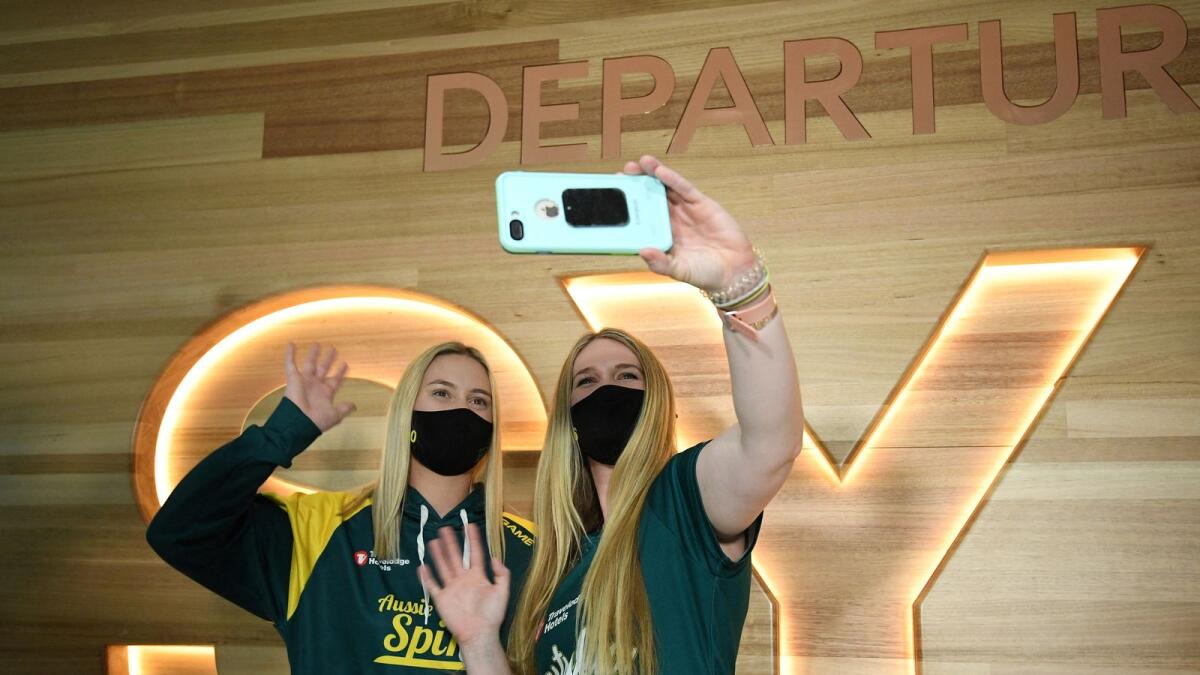 Australian softball players Shannon Keevers (left) and Ellen Roberts wave while on a video chat as they prepare to leave for the Tokyo Olympics. (AFP)