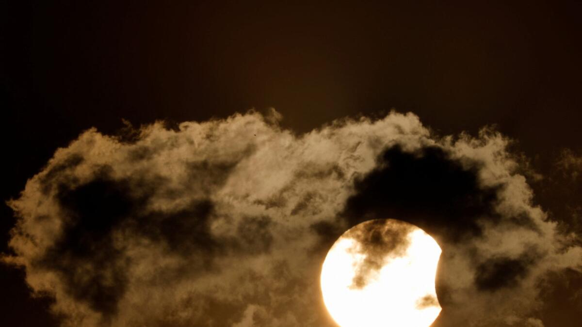 The partial eclipse seen behind a cloud during the sunset in Kathmandu, Nepal. (Reuters)