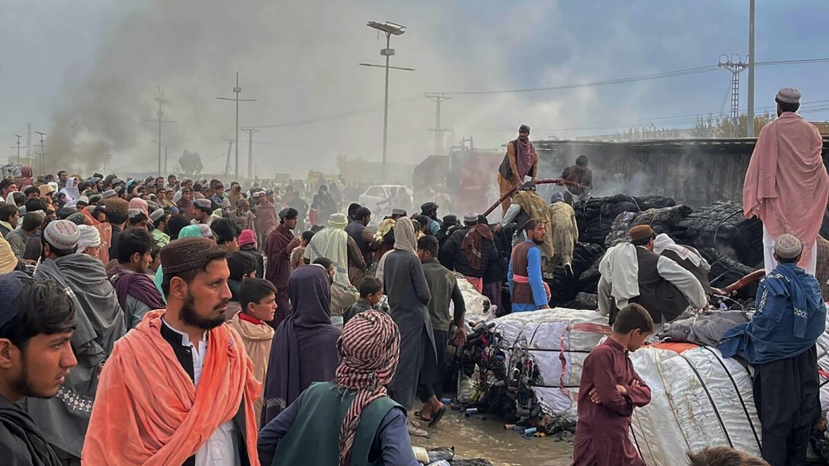 People gather beside a burnt truck caused by Afghan forces shelling in Chaman, a town in Pakistan's southwestern along Afghan border, on Sunday. — AP