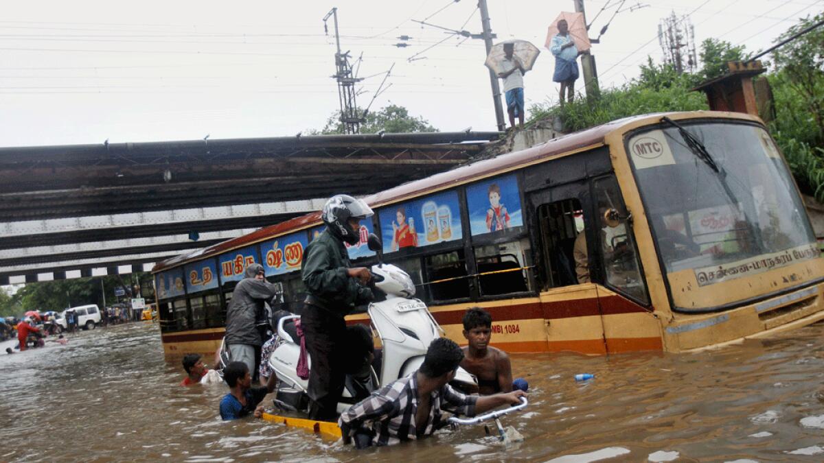 People help a man carry his two-wheeler on a cycle cart as they wade through a waterlogged subway in Chennai.