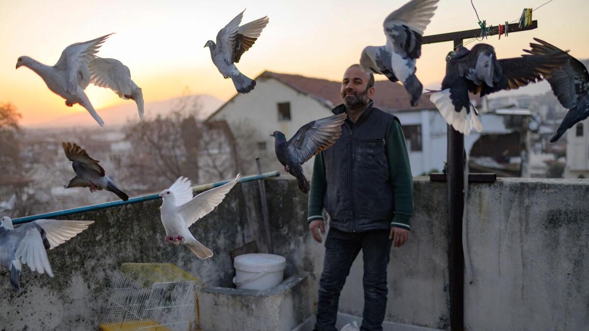 Murat Guzel scatters bird food on the roof of a restaurant where he worked before the earthquake, in Antakya south of Hatay, on February 17, 2023, after the 7.8-magnitude earthquake which struck parts of Turkey and Syria. — AFP