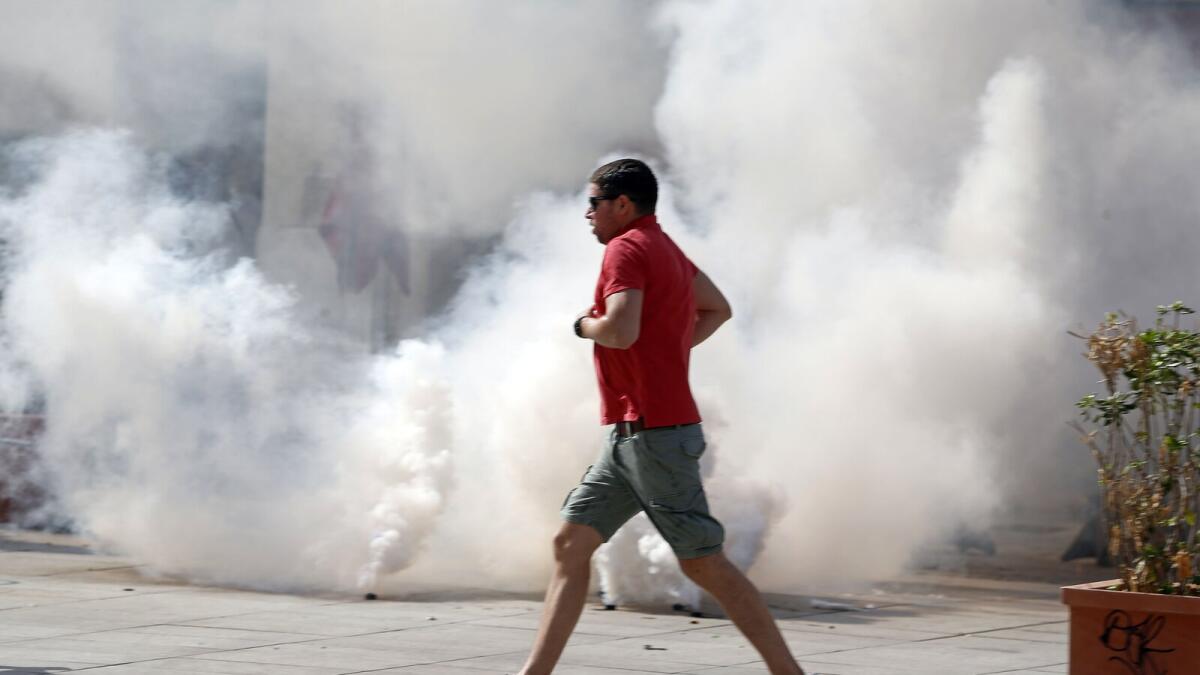 An England supporter runs past tear gas through the streets in downtown Marseille, France, Saturiday, June 11, 2016.