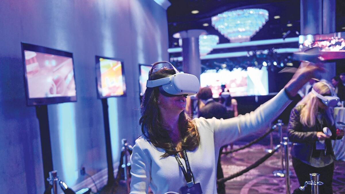 Attendees use a virtual reality (VR) headset during a presentation from March Gaming during the Milken Institute Global Conference in Beverly Hills, California on May 4, 2022. (Photo by Patrick T. FALLON / AFP)