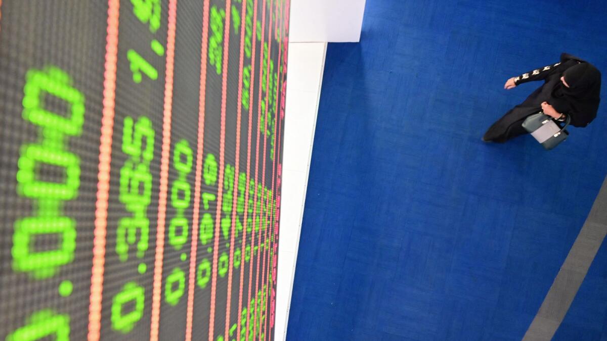 A woman underneath a digital board displaying stock data at the Dubai Financial Market. — AFP file