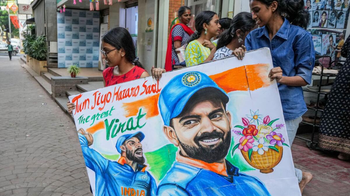 Artists give final touches to a painting of Virat Kohli in Mumbai. — PTI