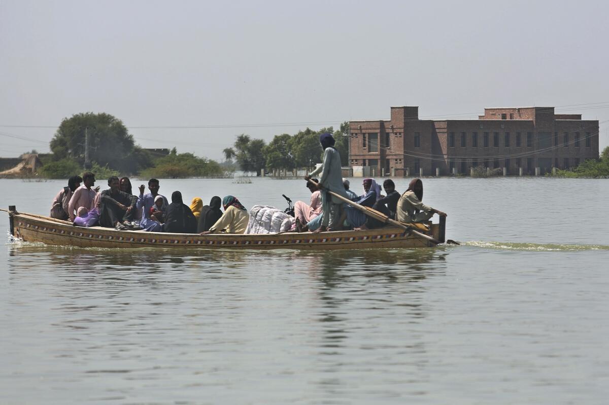 Villagers with their belongings and motorcyclists cross a flooded area through a boat in Dadu, a district of southern Sindh province, Pakistan, on September 23, 2022. — AP file
