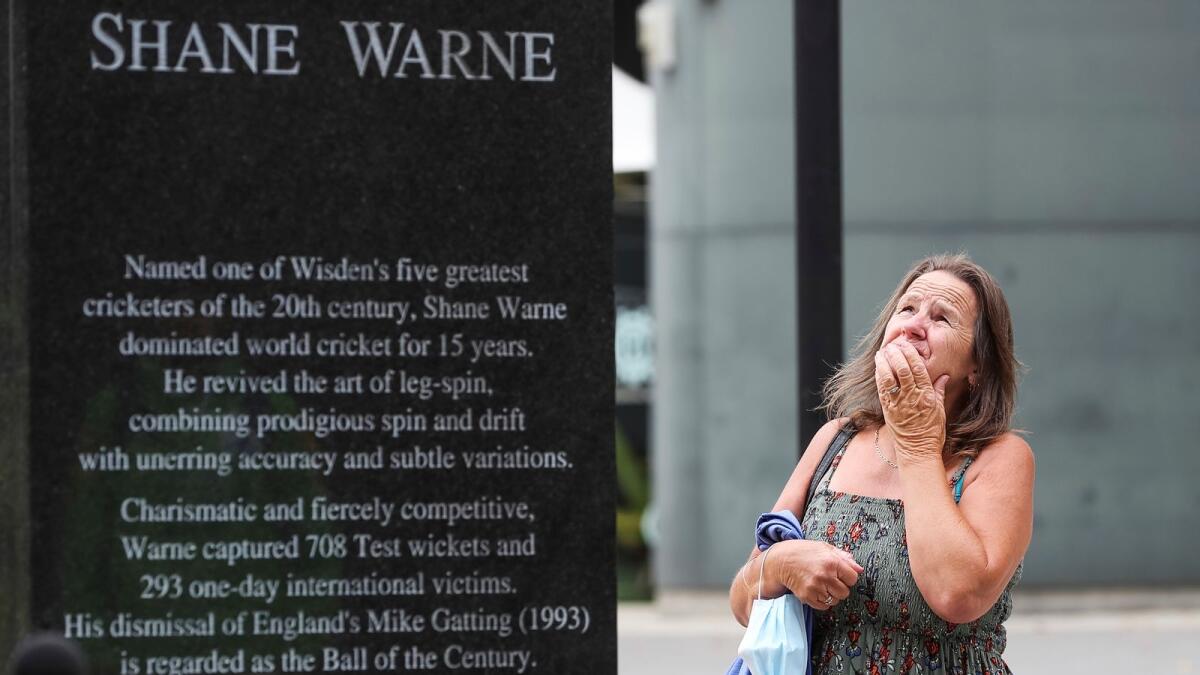 A woman pauses at the statue of cricket legend Shane Warne outside the Melbourne Cricket Ground on Saturday. Warne died of a suspected heart attack on Friday in Thailand. He was 52. (AP)