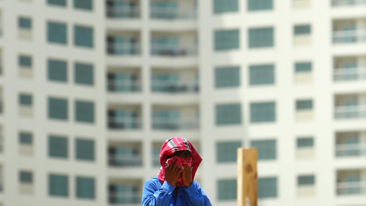 A worker wipes sweat during the construction of a new project in the background of a huge concrete tower in Dubai.- Photo by Shihab/ Khaleej Times