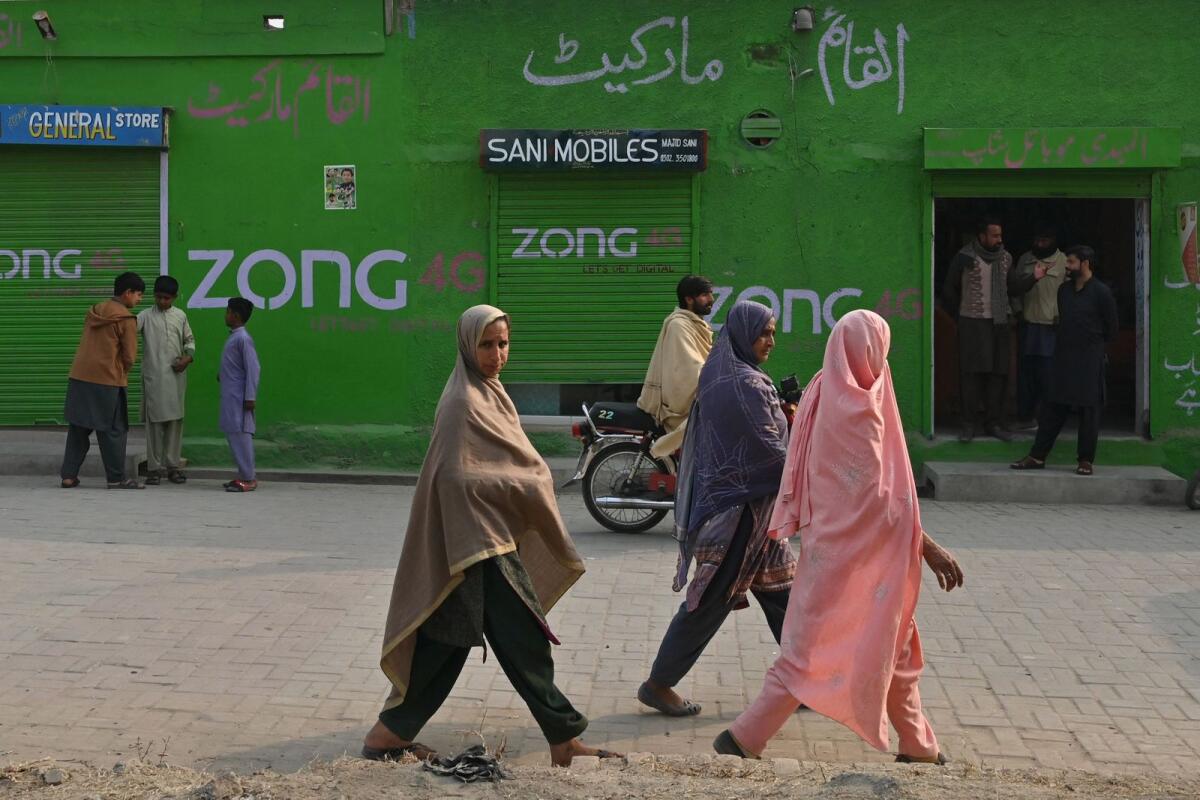 Women look on as they walk along a street in Dhurnal of Punjab Province, ahead of the upcoming general elections. — AFP