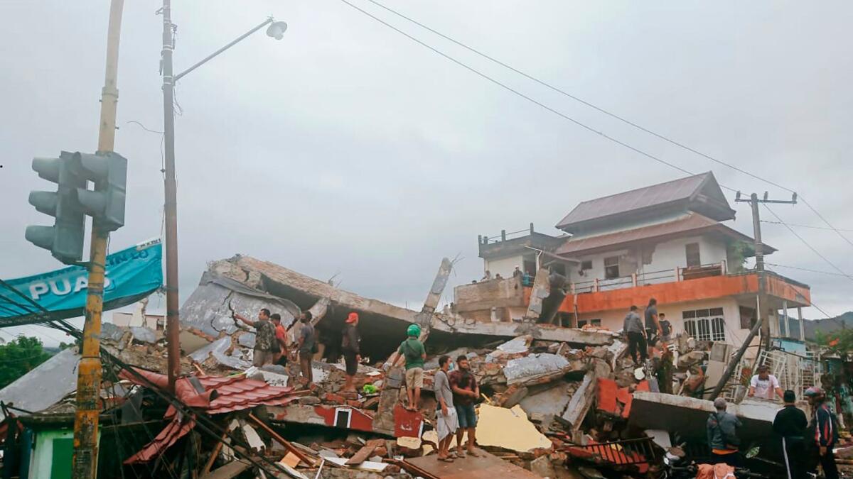 Residents inspect an earthquake-damaged buildings in Mamuju, West Sulawesi, Indonesia.  AP