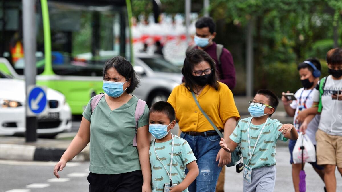 People wearing face masks cross a road in Singapore, on May 14, 2021.