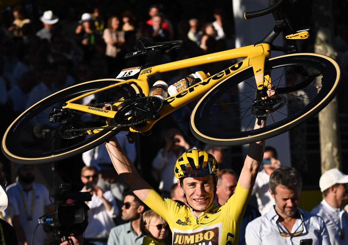 Jumbo-Visma's Jonas Vingegaard raises his bicycle as he celebrates winning the Tour de France in Paris on Sunday. — AFP