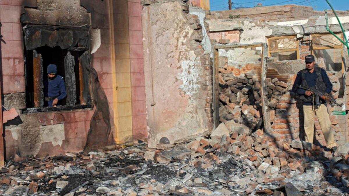 Policemen inspect the burnt Hindu temple in a remote village in Karak district of Pakistan. — AFP
