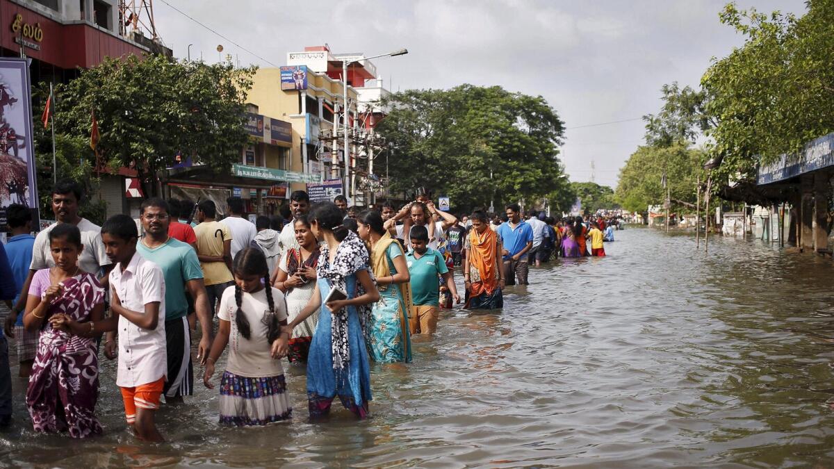 People stand on a flooded road in Chennai, India, December 2, 2015.