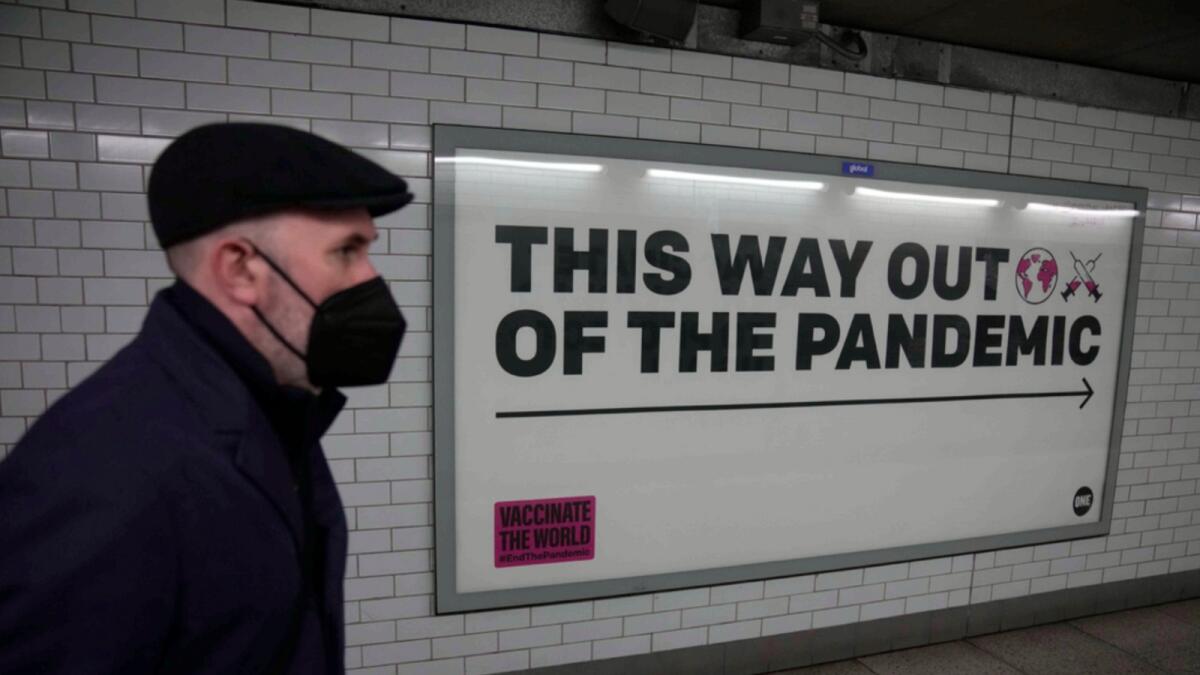 A man wearing a face mask walks past a health campaign poster from the One NGO, in an underpass leading to Westminster underground train station. — AP
