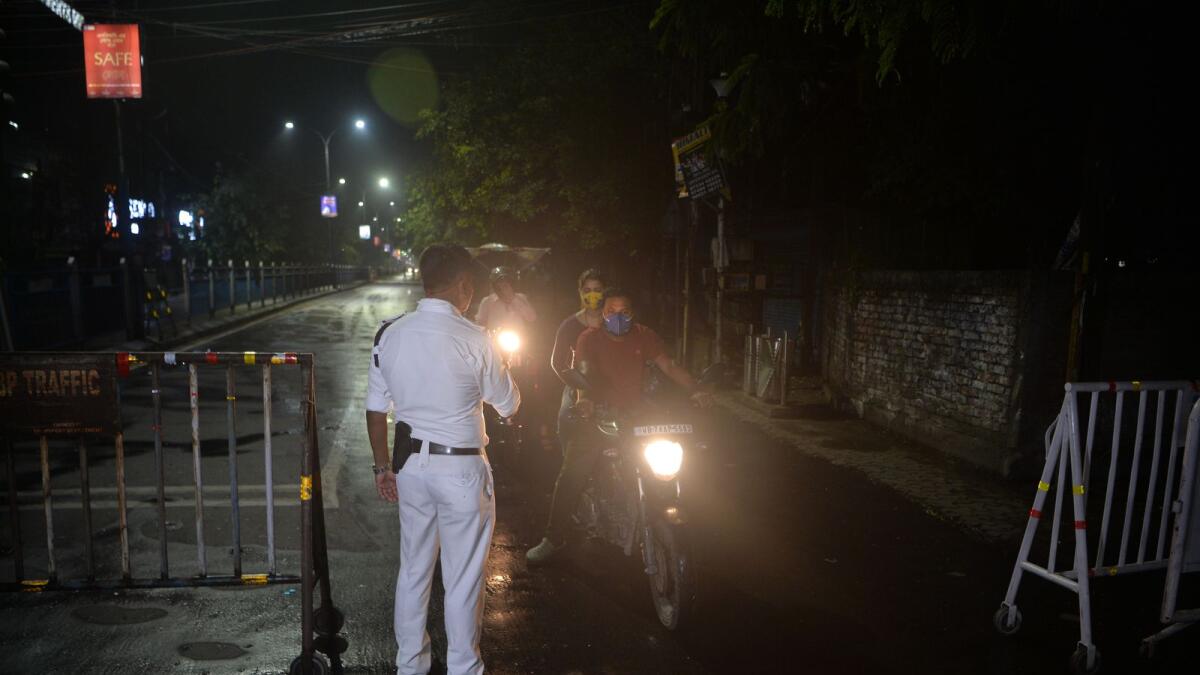 A policeman checks the movement of motorists after night curfew was imposed by the state administration to curb the spread of the Covid-19 coronavirus in Siliguri on May 16, 2021. (Photo: AFP)