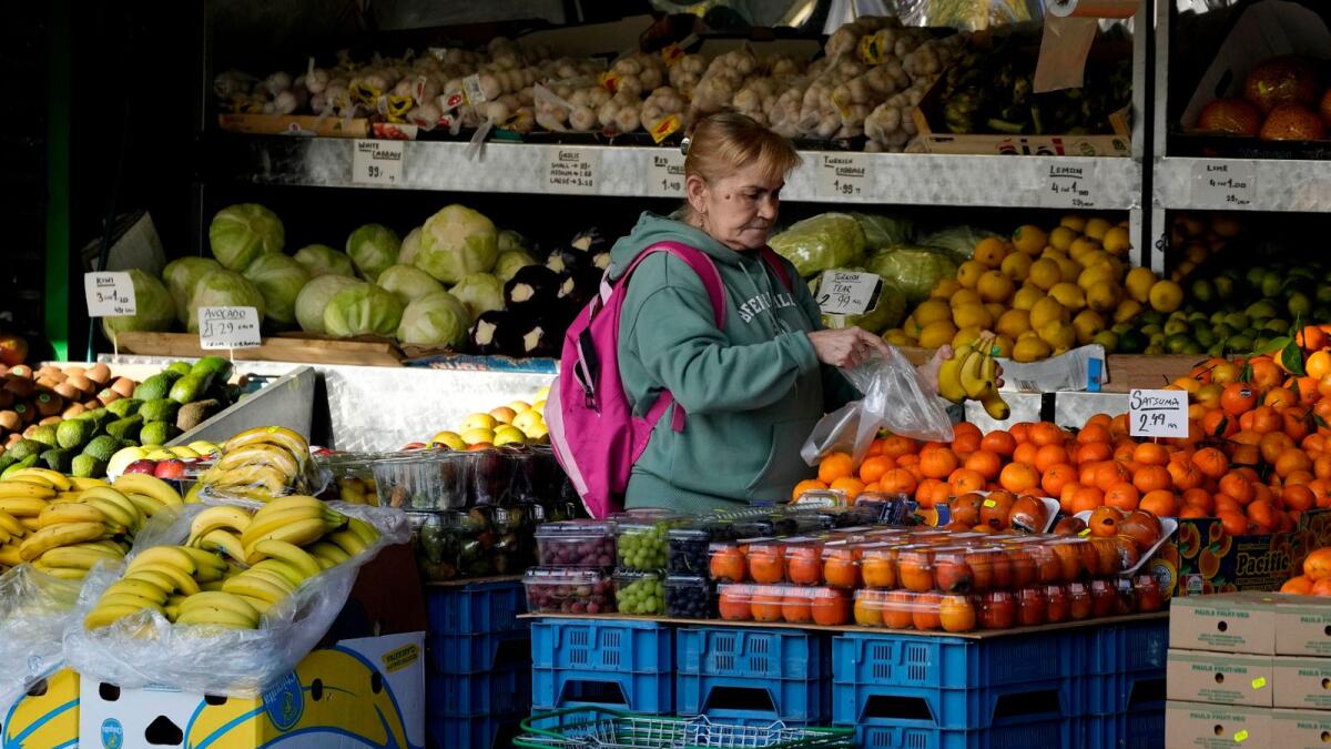 A woman selects fruits at a supermarket in London. Britain’s economy bounced back sharply last year and recovered its pre-pandemic size in November 2021. But fast-rising inflation means the Bank of England expects the economy will slip back into recession later this year. — AP file photo
