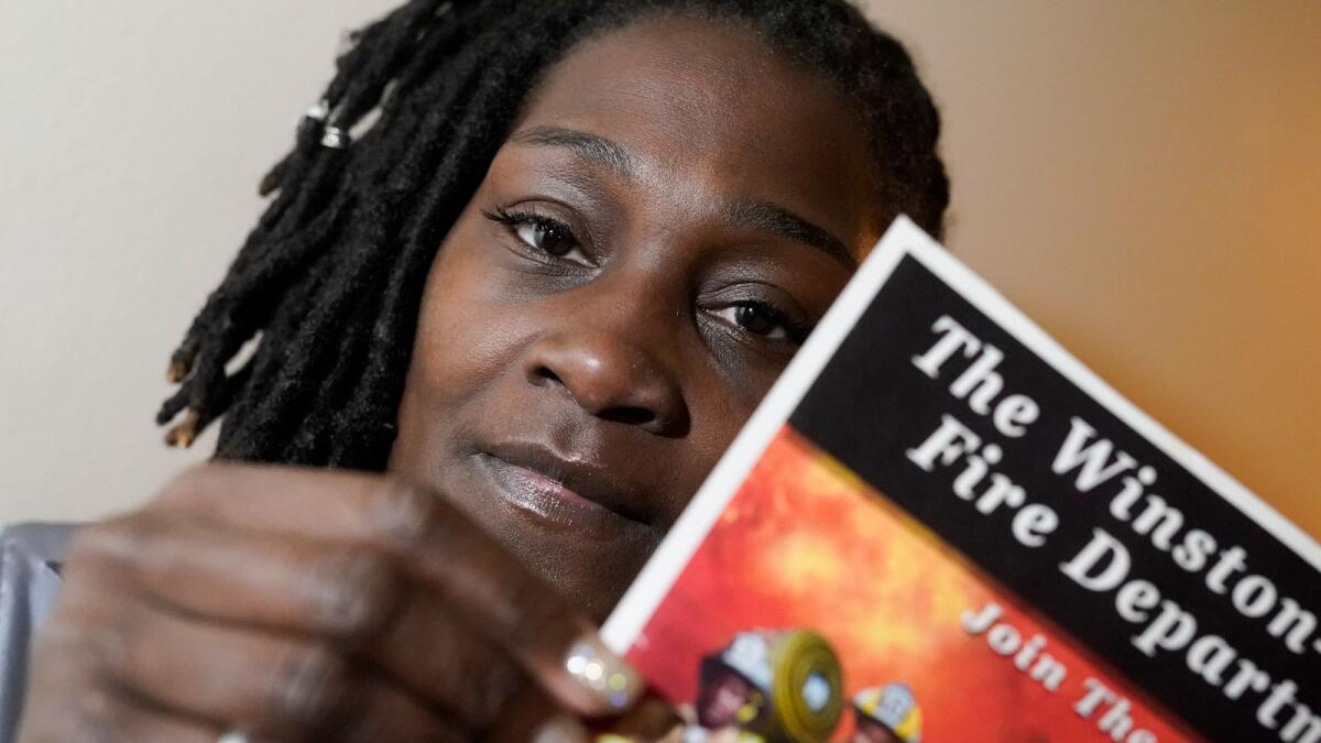Timika Ingram poses for a picture holding a flyer when she was a firefighter on November 19, 2020, in Charlotte, North Carolina.