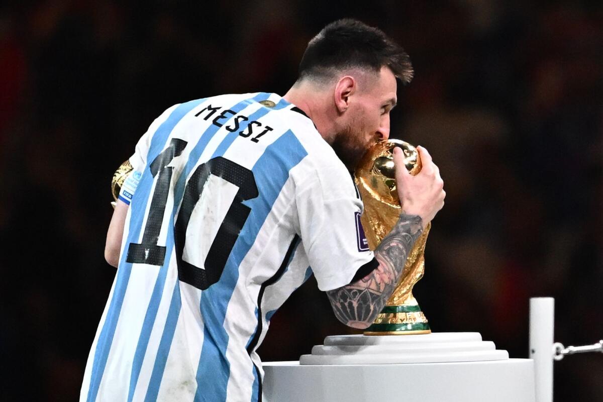 Argentina's forward #10 Lionel Messi holds the Golden Ball award for best player as he kisses the FIFA World Cup Trophy. Photo: AFP