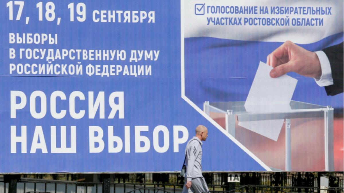 A pedestrian walks past a board informing of the upcoming Russian parliamentary elections in a street in the rebel-held city of Donetsk, Ukraine. — Reuters