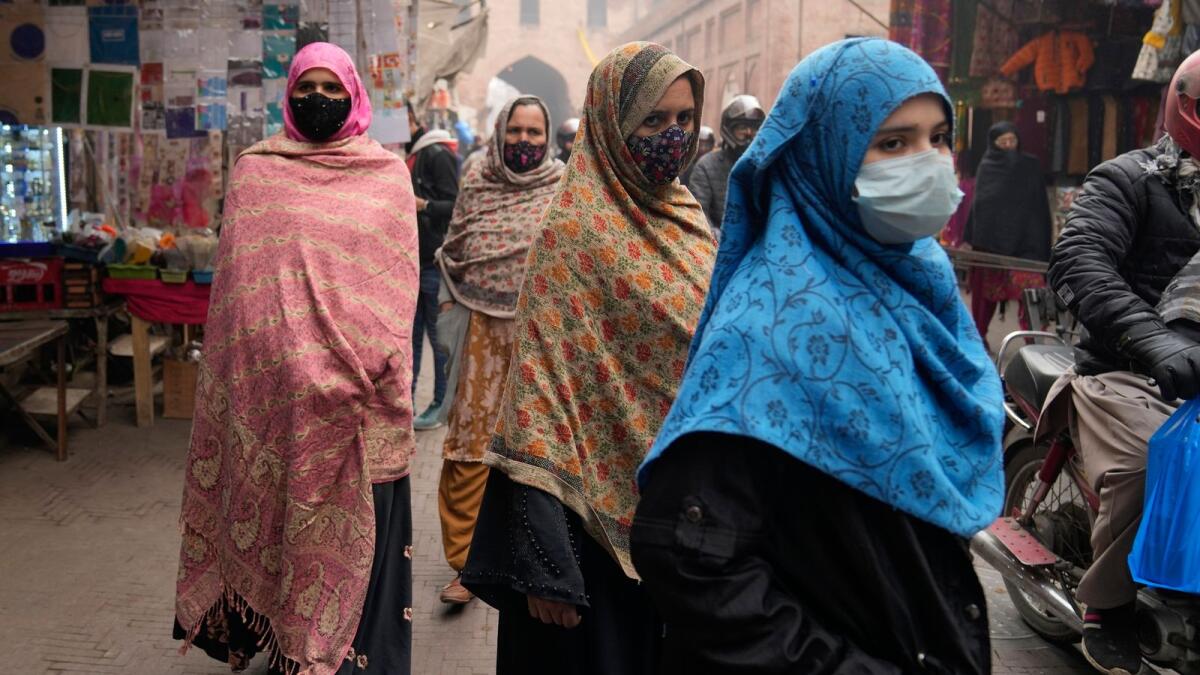 Women, wearing masks, visit a market in Lahore on January 15, 2024. — AP